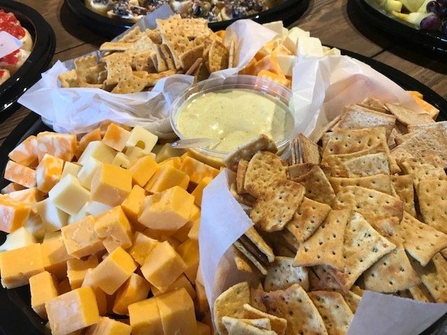 Assorted crackers and cubed cheese with a creamy dip on a party tray