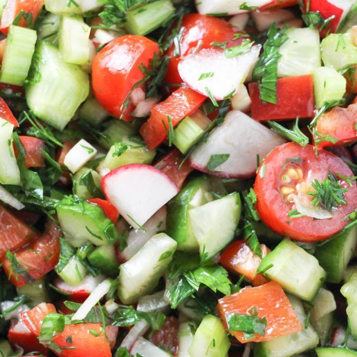 Close-up of fresh cucumber, tomato, and radish salad with chopped herbs
