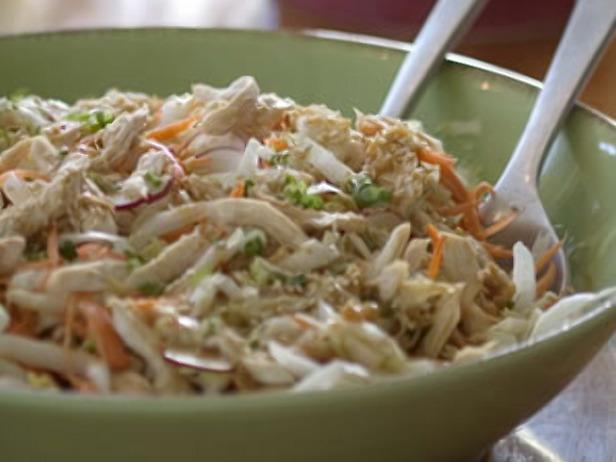 Bowl of creamy coleslaw with shredded cabbage and carrots, served with two spoons
