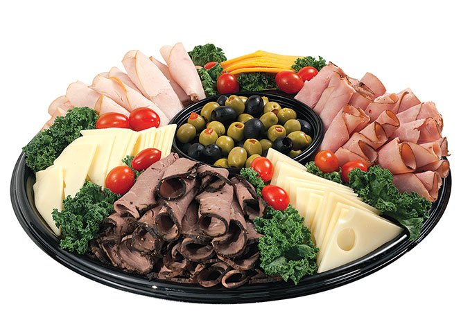 Assorted cold cut and cheese platter with olives, tomatoes, and garnishes on a round tray