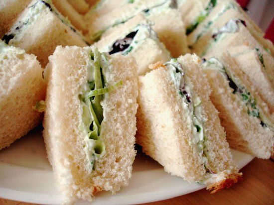 Triangular cucumber and cream cheese tea sandwiches on a white plate
