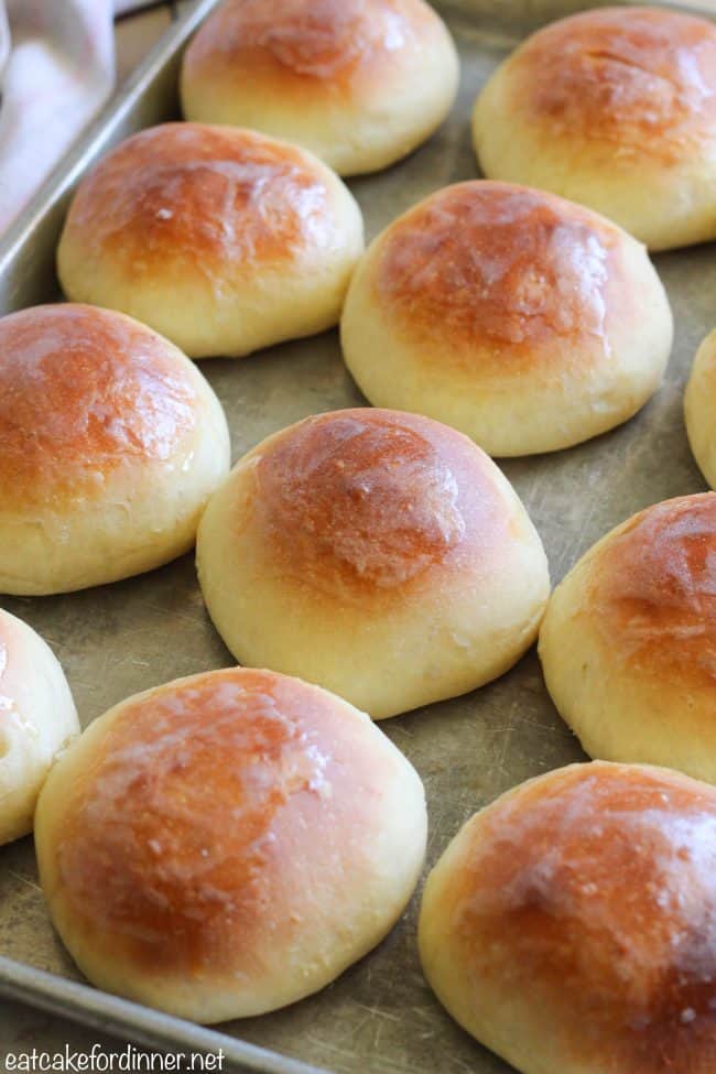 Fresh golden-brown dinner rolls baking on a tray
