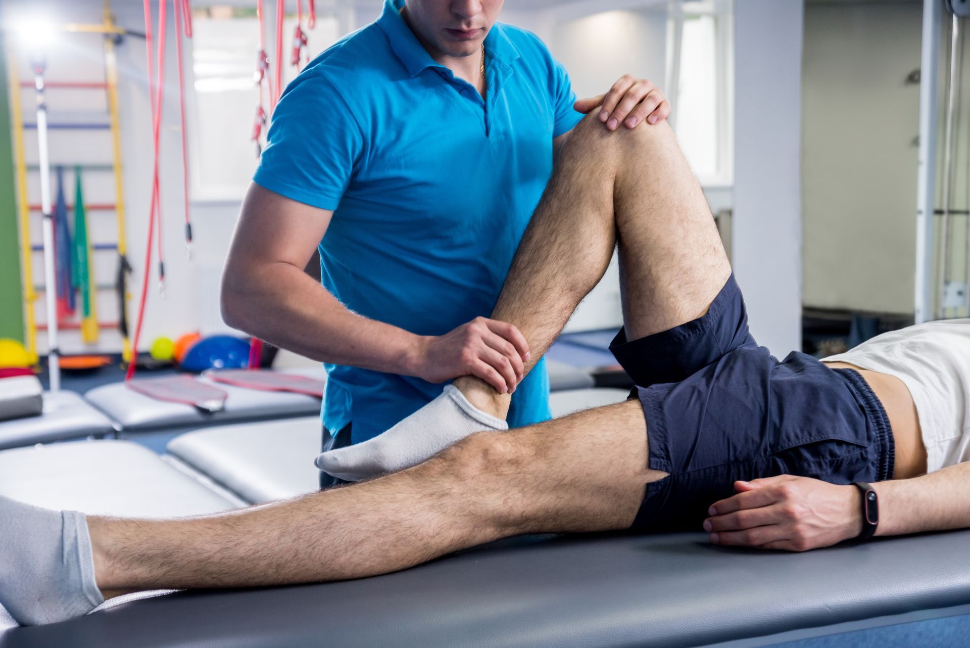 A male physiotherapist is working on the leg of a patient after a possible sports injury.