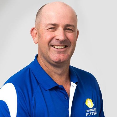 Man in blue polo shirt smiling, Chambers Physiotherapy logo on shirt.