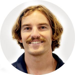 Man with brown hair and mustache smiling, wearing a dark blue shirt.