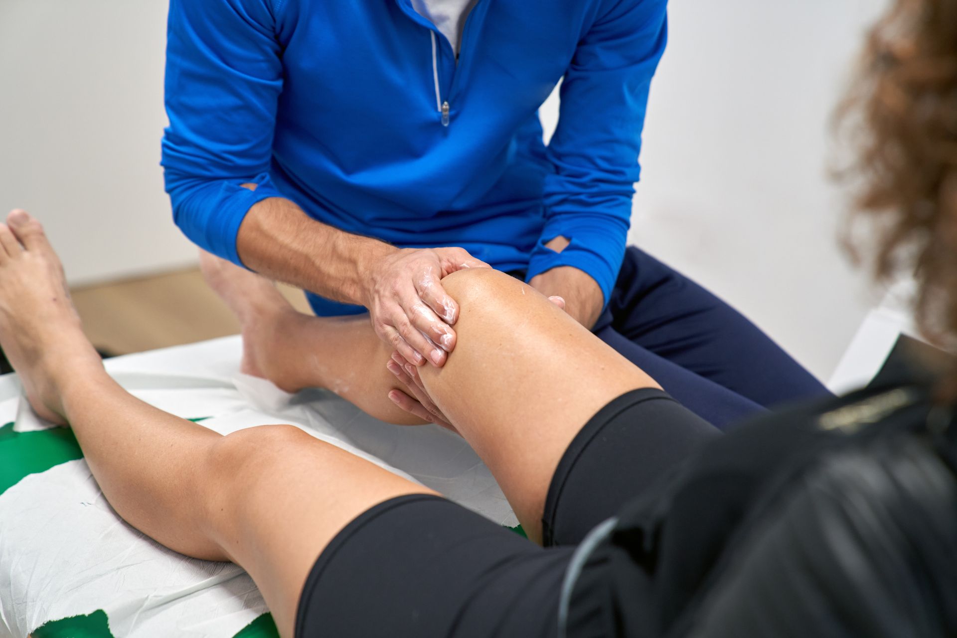 Physical therapist manipulates a patient's knee during an examination.