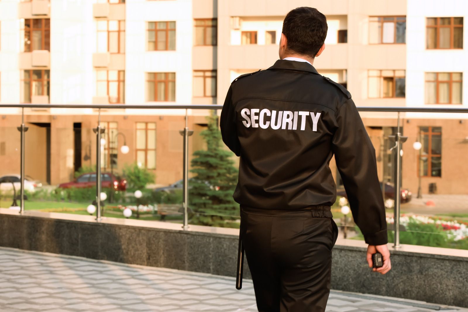 A security guard is walking in front of a building.