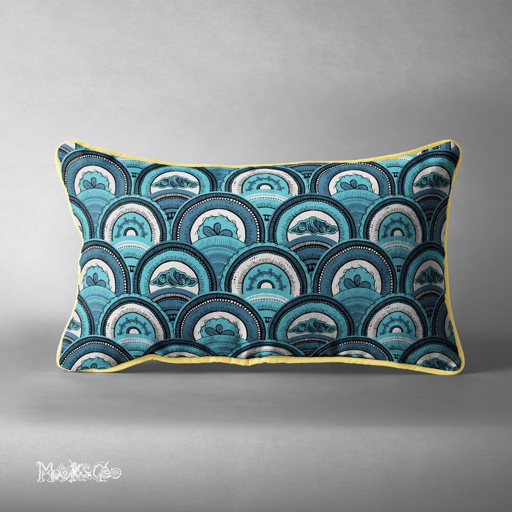 Overlapping circles or shells repeat pattern on a rectangular statement cushion, with clouds and flowers, using different blue tones. Illustration by MooksGoo