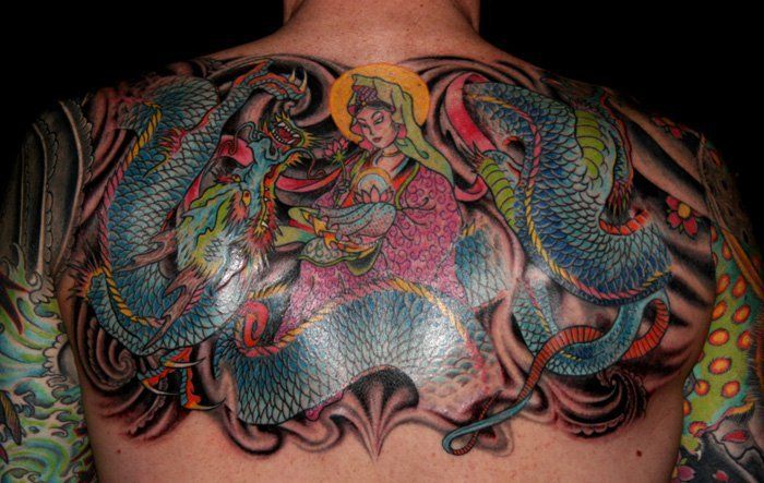 Colorful back tattoo of a mermaid surrounded by dragons and swirling waves