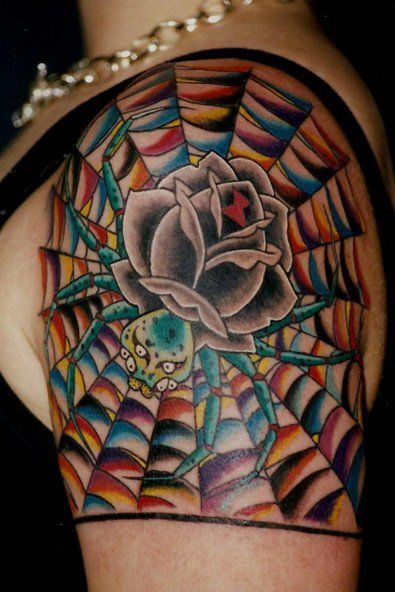 Colorful rose tattoo on shoulder and upper arm with a black spiderweb background
