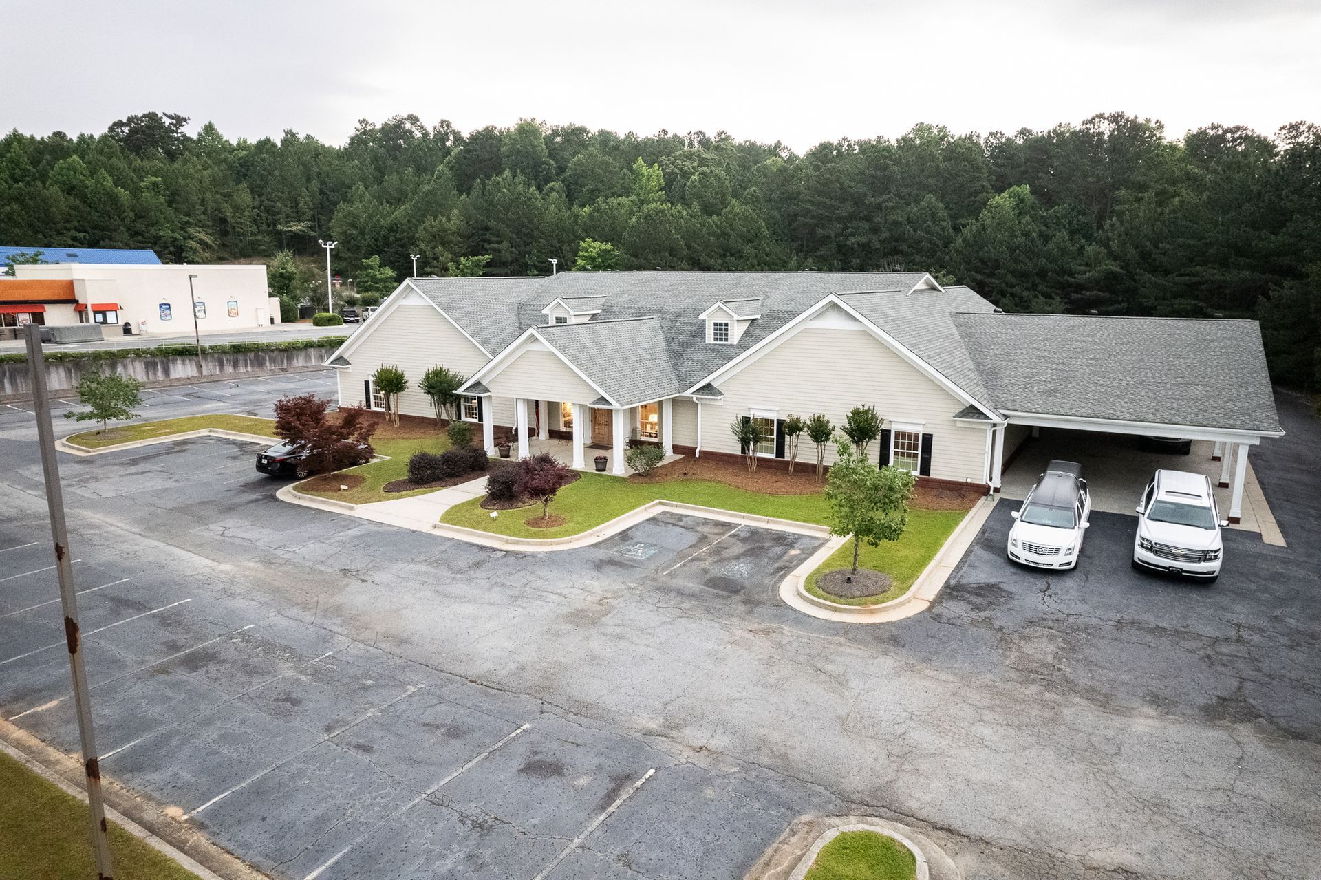 Aerial view of a beige apartment building with parked cars and trees in the background