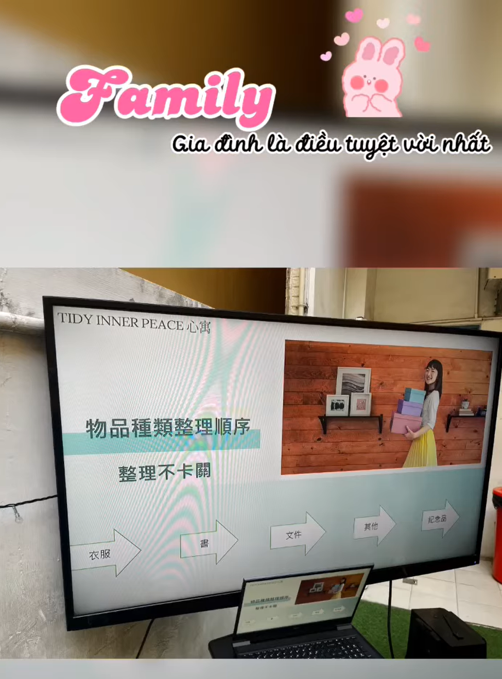 電視螢幕上顯示著中文文字和圖片。螢幕前放著一台筆記型電腦。螢幕左上角寫著「家庭」字樣。