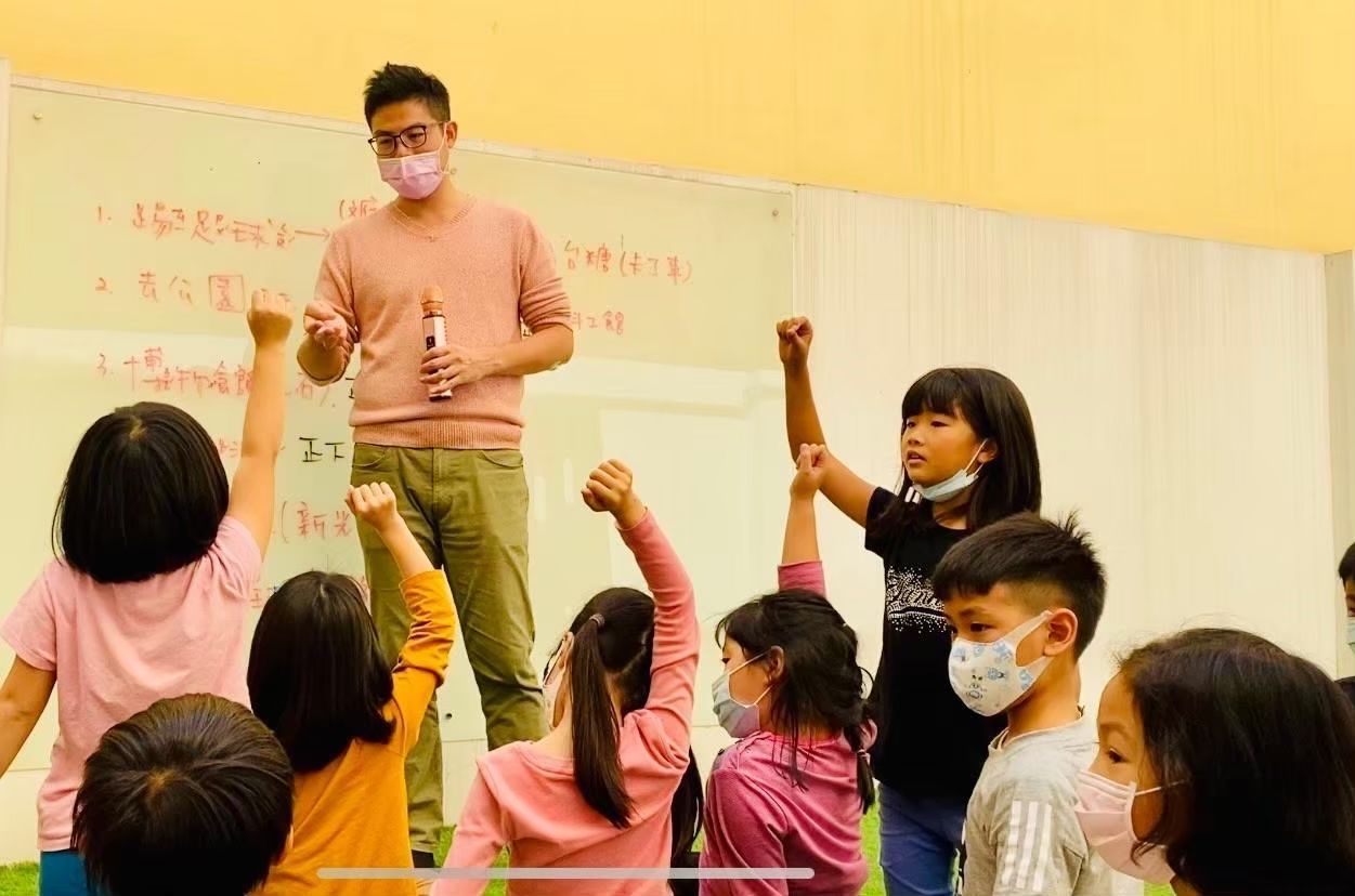 安親班教室裡,老師戴著口罩,孩子們舉手。