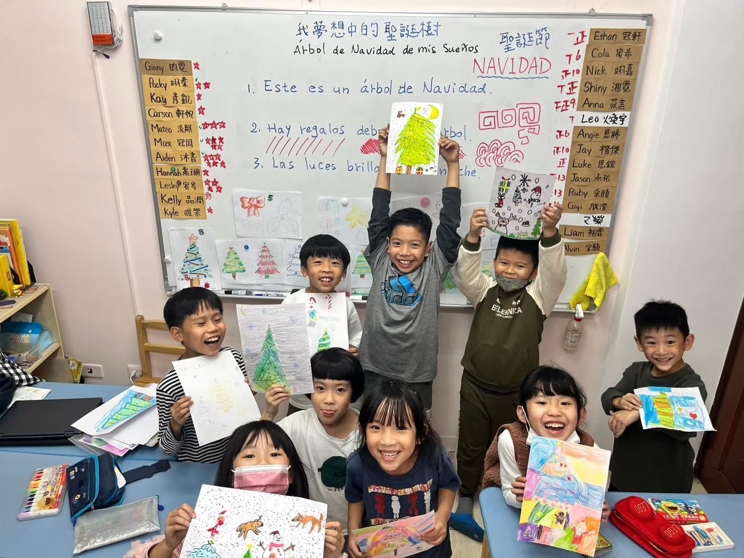 教室裡的孩子們舉著畫作。他們身後的白板上寫著韓文。