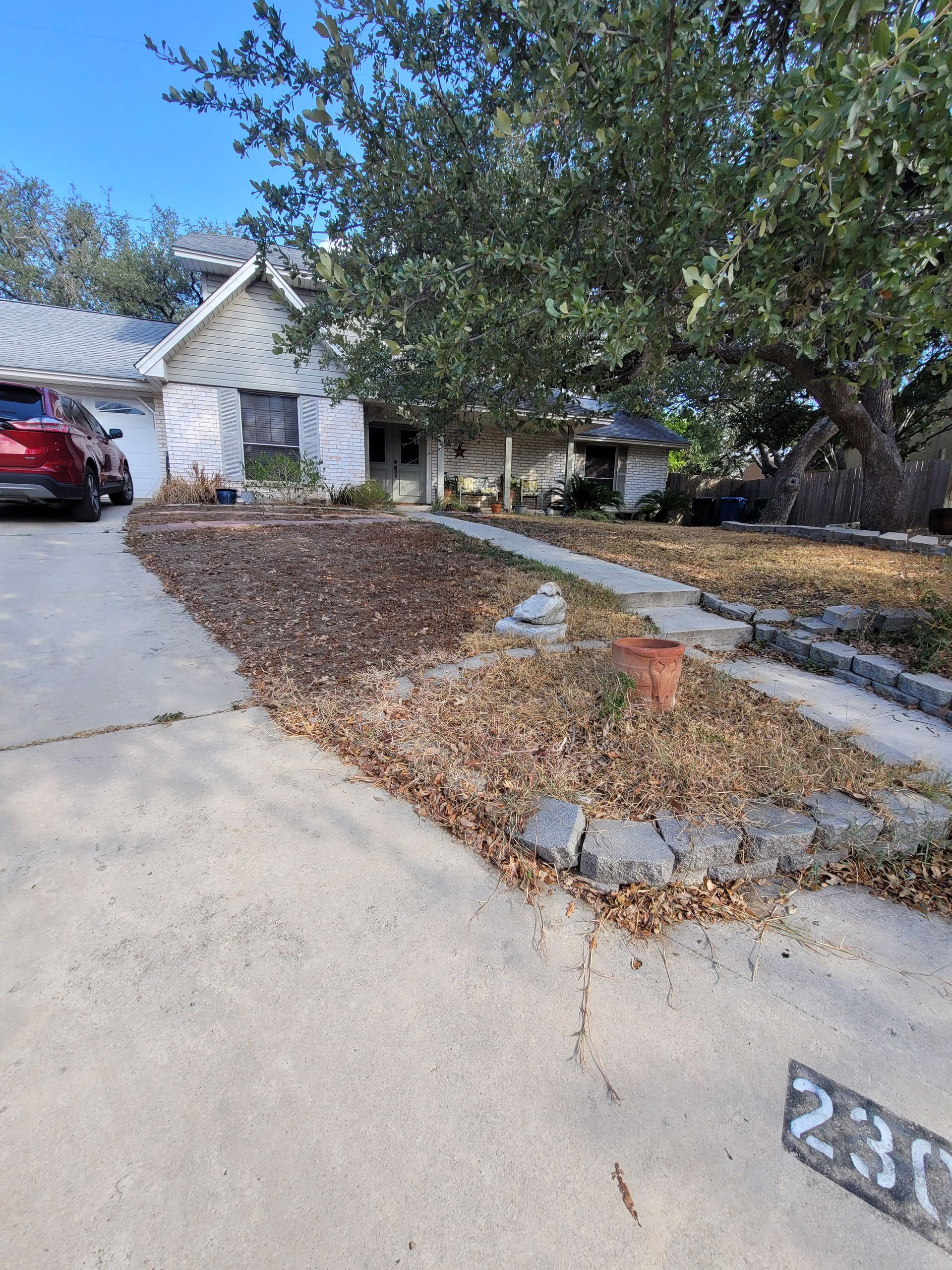 A red car is parked in the driveway of a house .