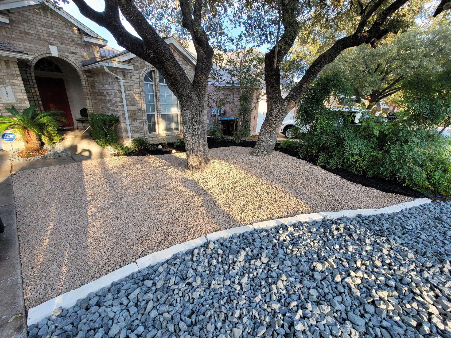 A driveway filled with gravel and rocks in front of a house .