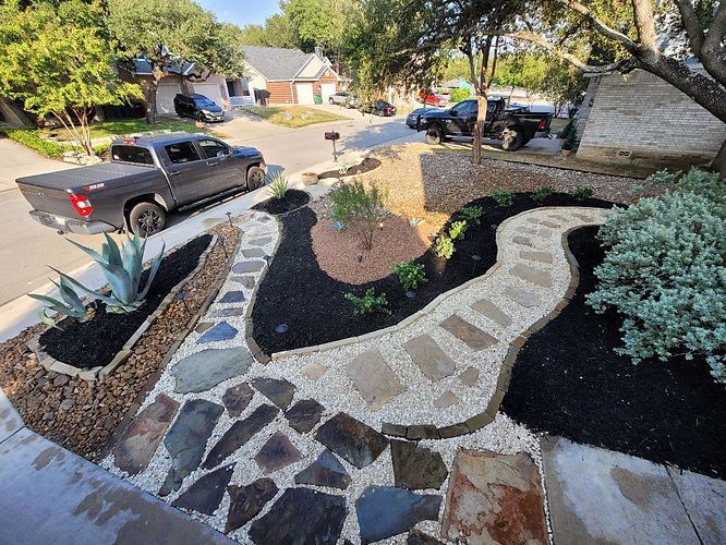 A truck is parked on the side of the road next to a stone walkway .