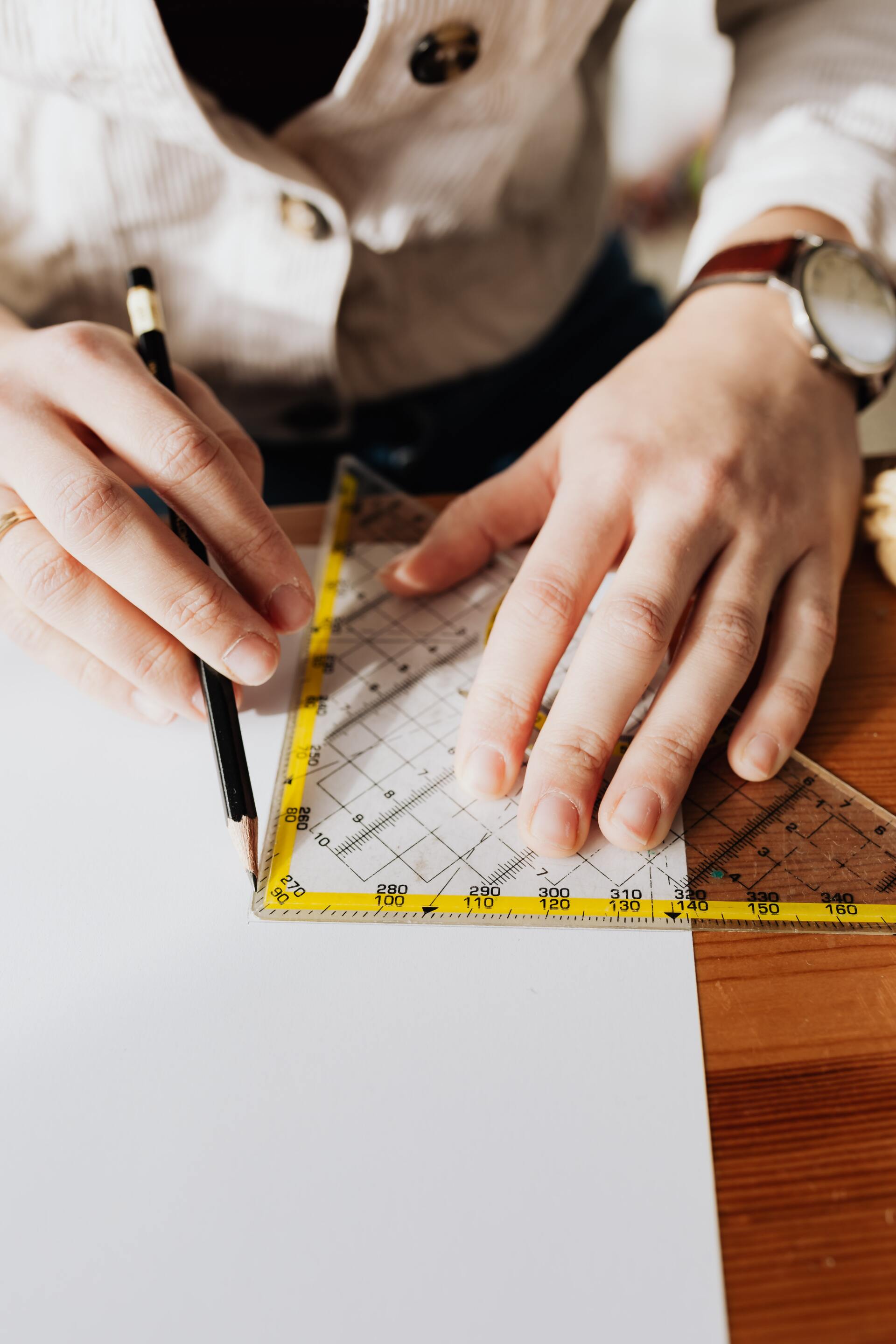 A person is using a ruler and pencil to draw a triangle on a piece of paper.