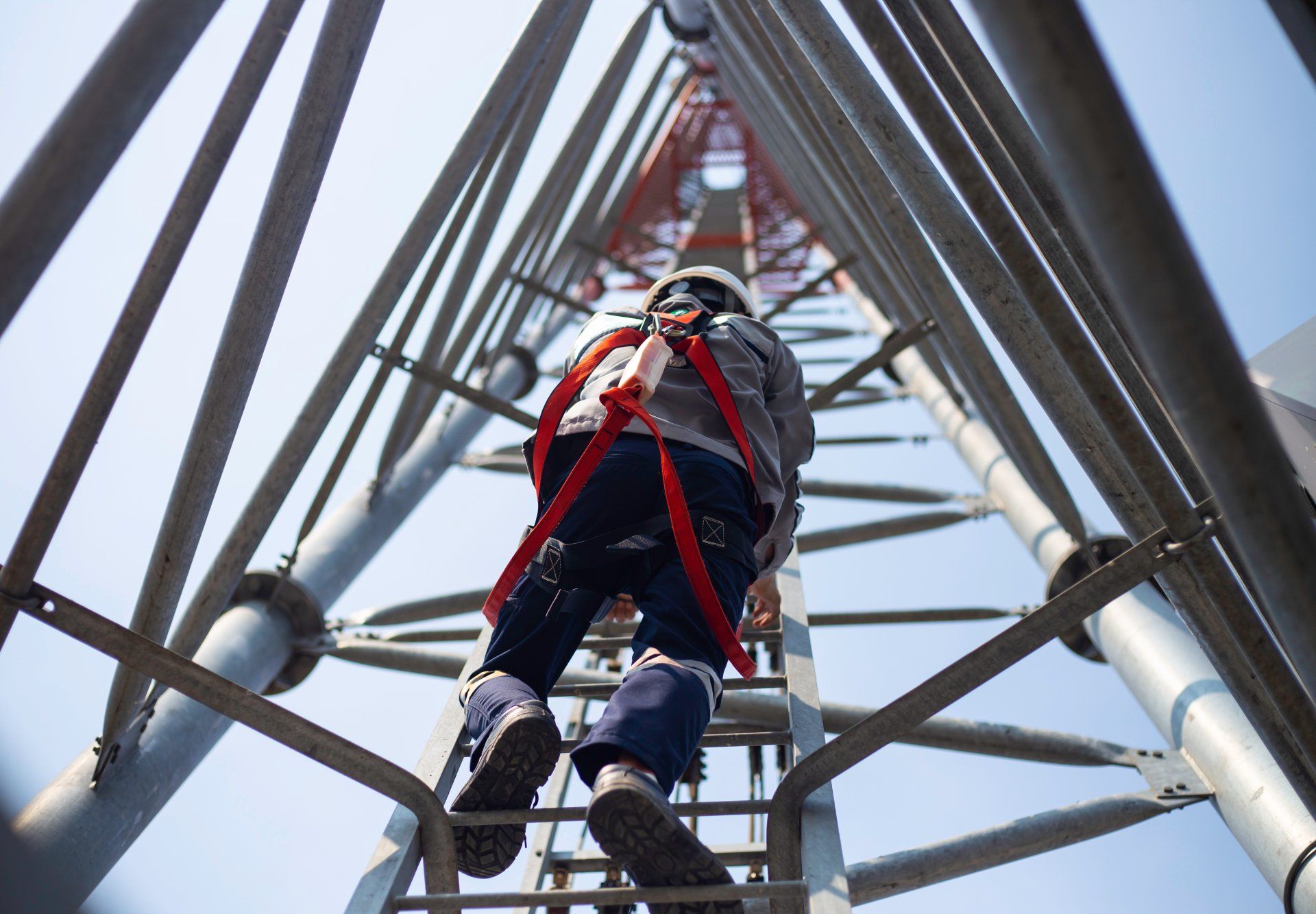 A man is climbing up a very tall metal structure.