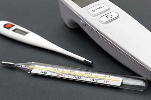 Un termómetro digital y un termómetro de vidrio sobre una mesa