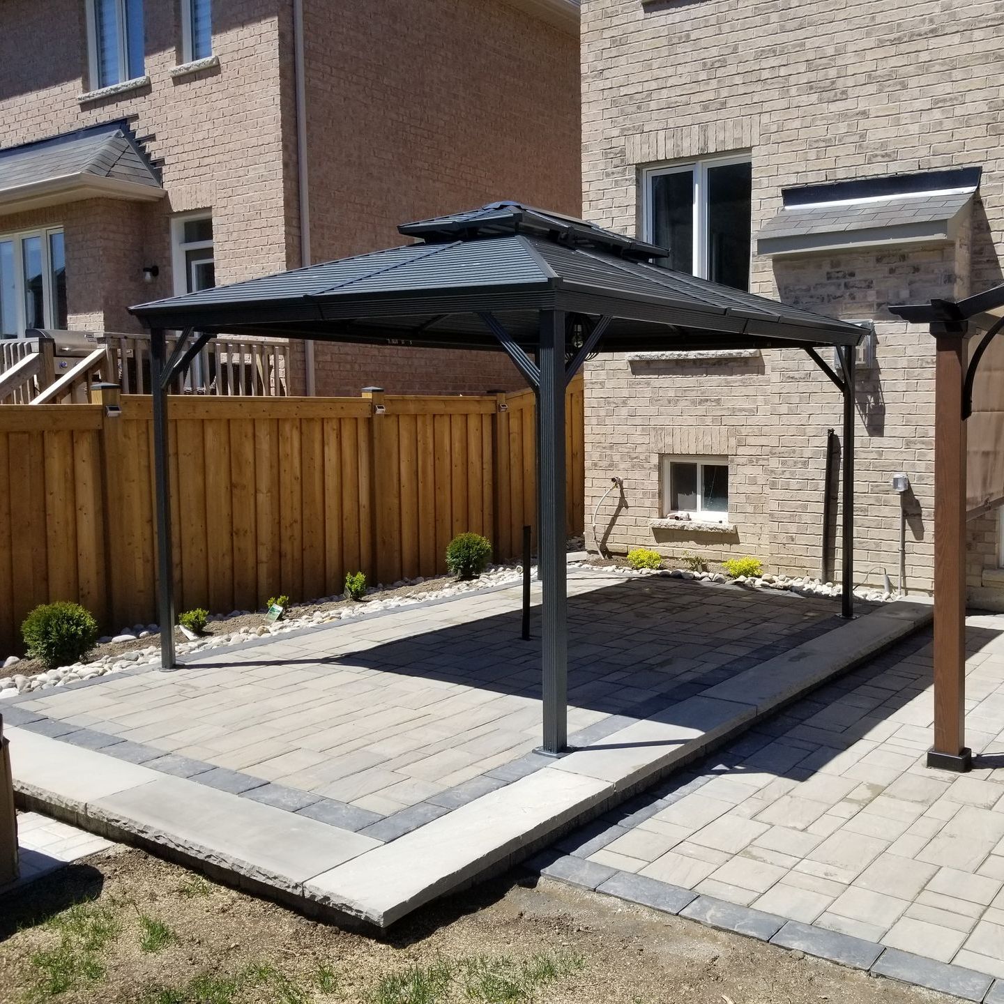 A gazebo in the backyard of a house with a wooden fence