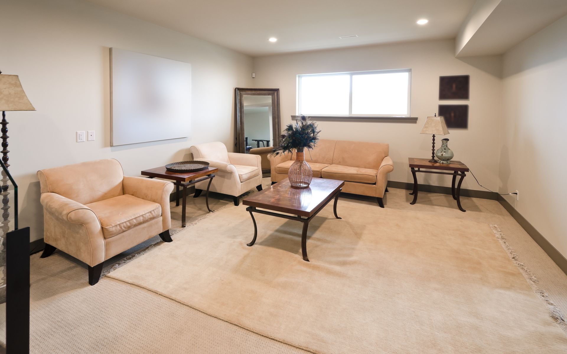 Living room with tan armchairs, sofa, rug, and dark wood tables.