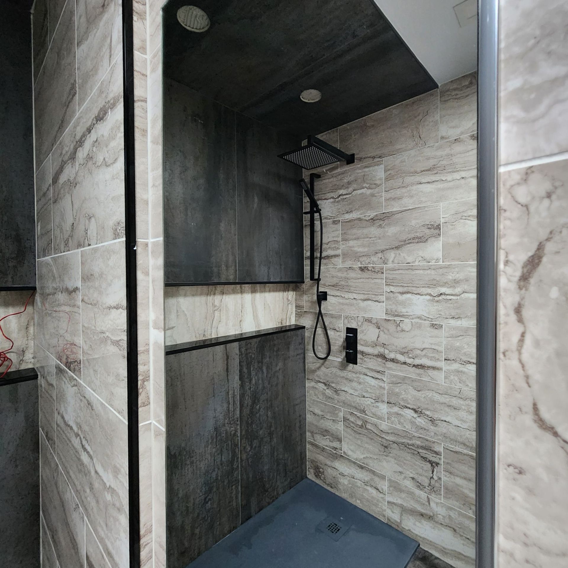 A walk in shower with a black shower head