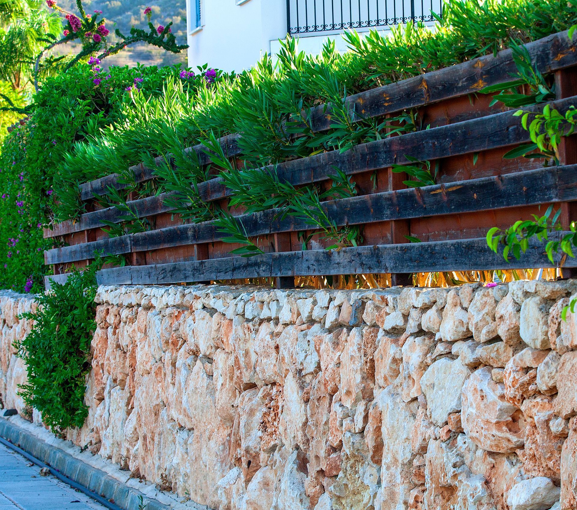A stone wall with a wooden fence surrounding it
