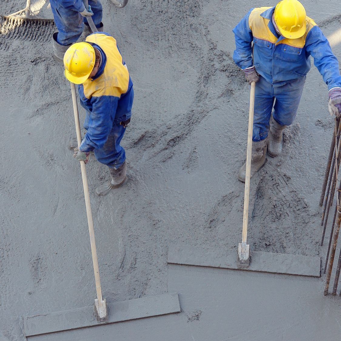 A group of construction workers are working on a concrete floor
