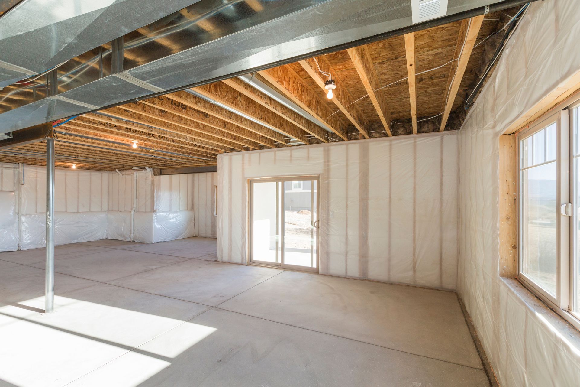 An empty basement with insulated walls and a sliding glass door.
