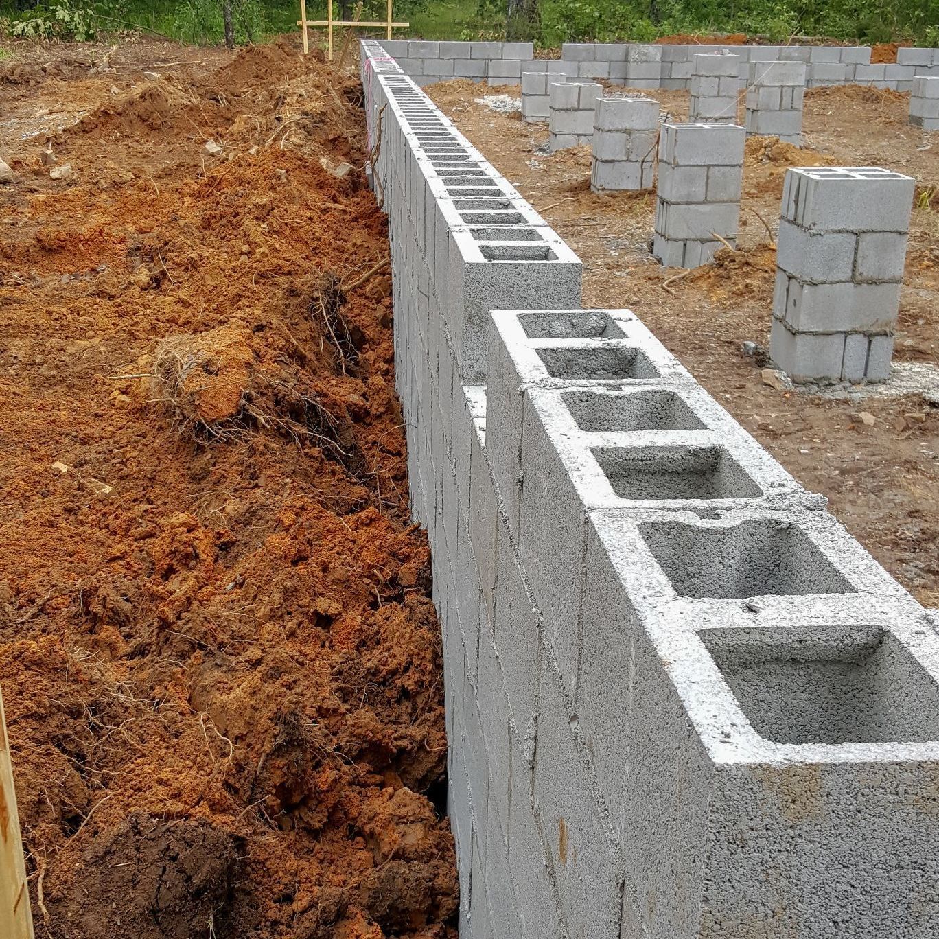 A brick wall is being built in the dirt