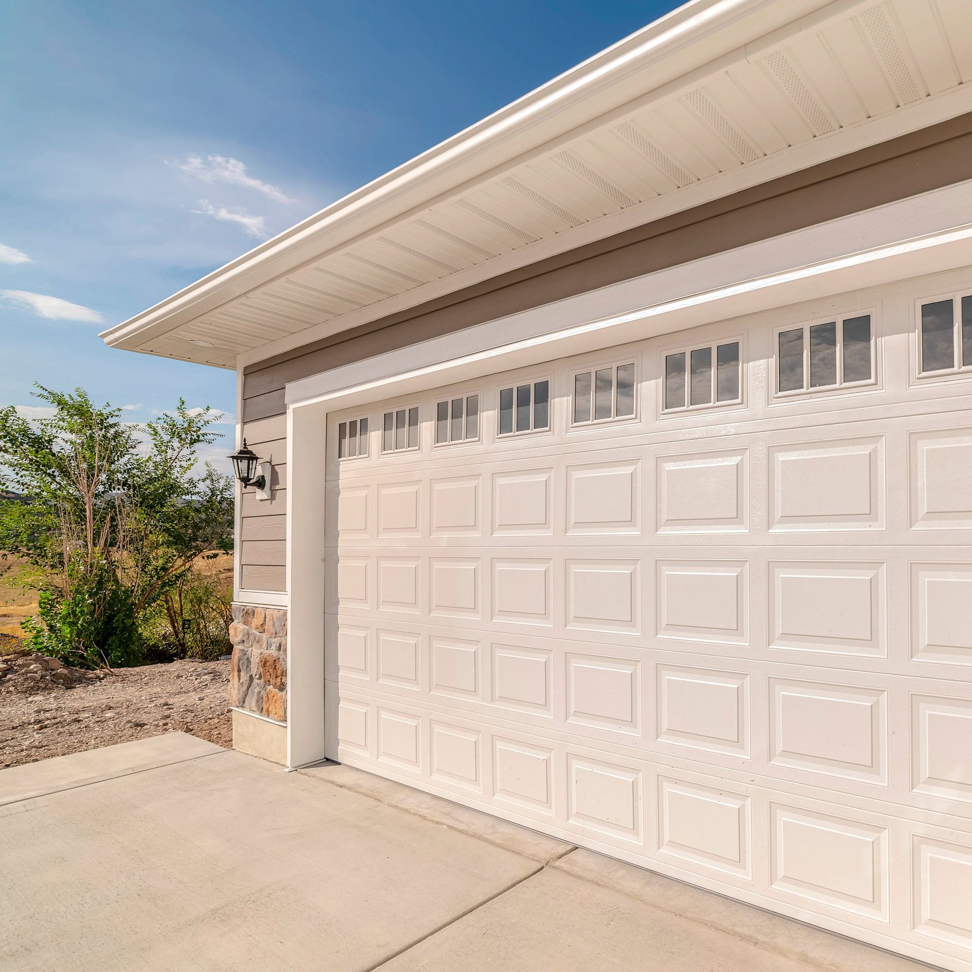 A white garage door is open on a sunny day.