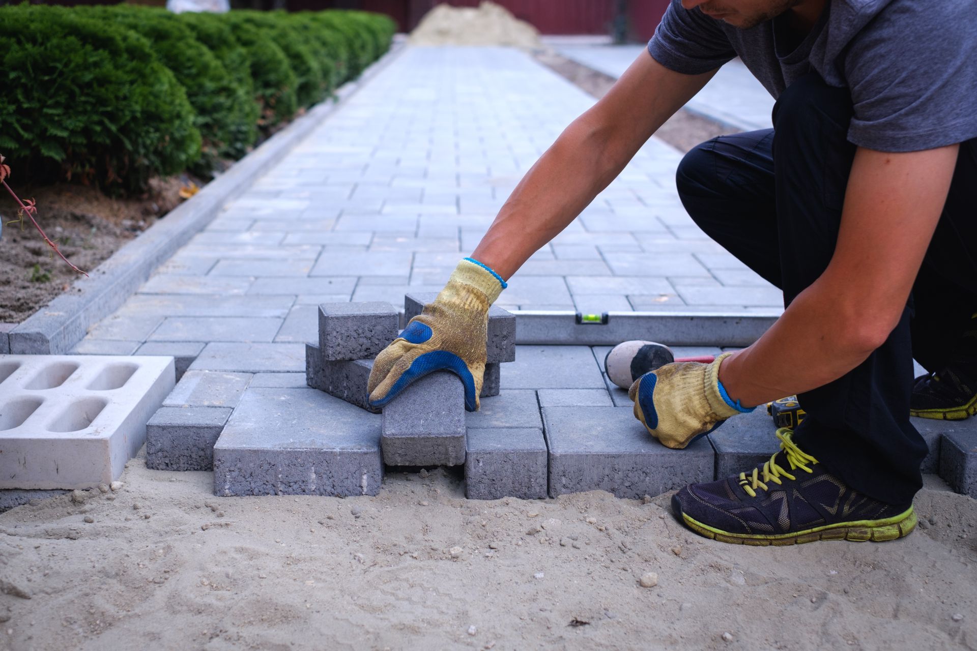 A man is laying bricks on a sidewalk.