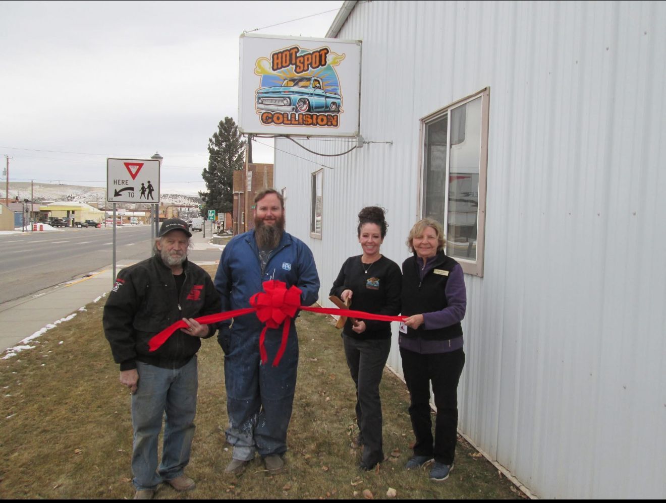 Four people cut a red ribbon in front of