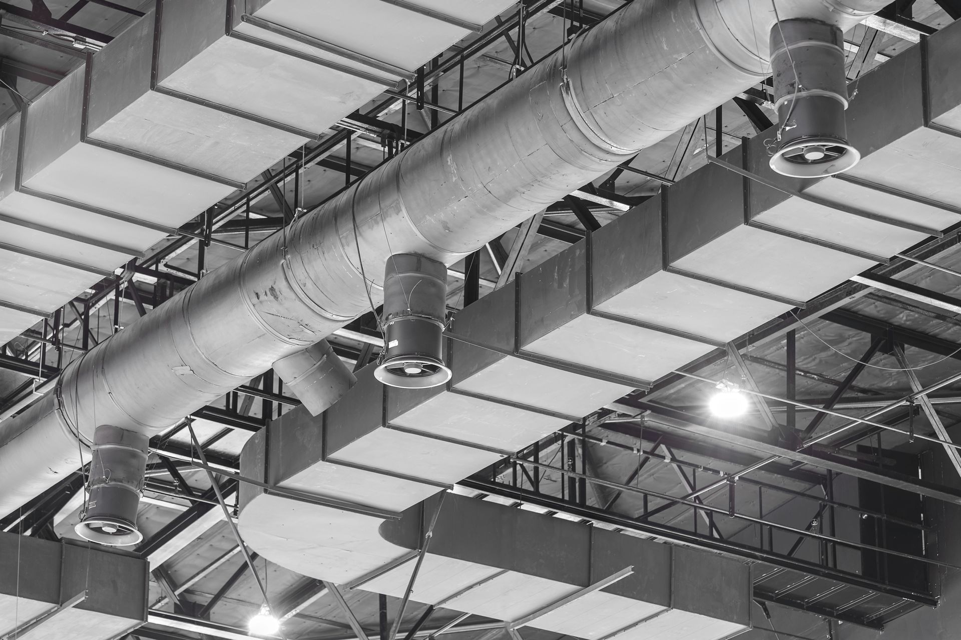 Condotti HVAC, prese d'aria e apparecchi di illuminazione sospesi a un soffitto in lamiera ondulata.