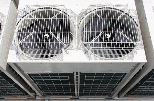 Due grandi ventilatori industriali con pale nere, montati su un'unità rettangolare bianca.