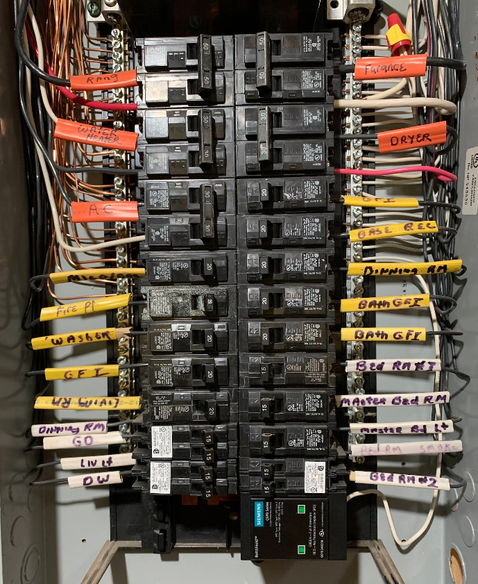 Electrical panel with labeled circuit breakers and wiring. Gray, black, and labeled wires, with a few white wires.