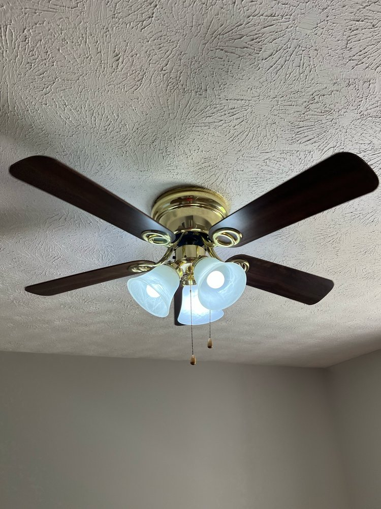 Ceiling fan with dark brown blades, gold accents, and three frosted glass lights.