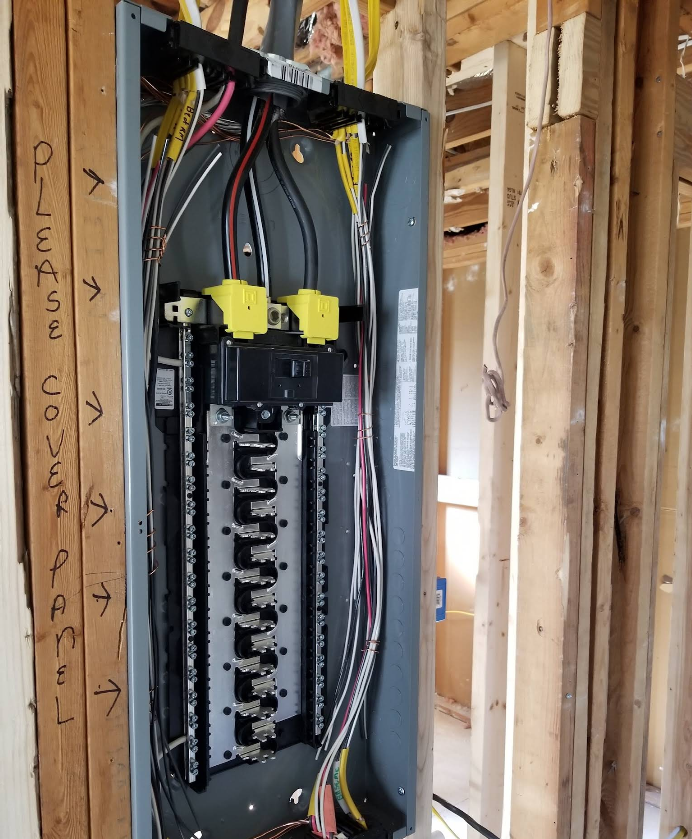 Electrical panel installed in a wooden frame. Wires connect to breakers.
