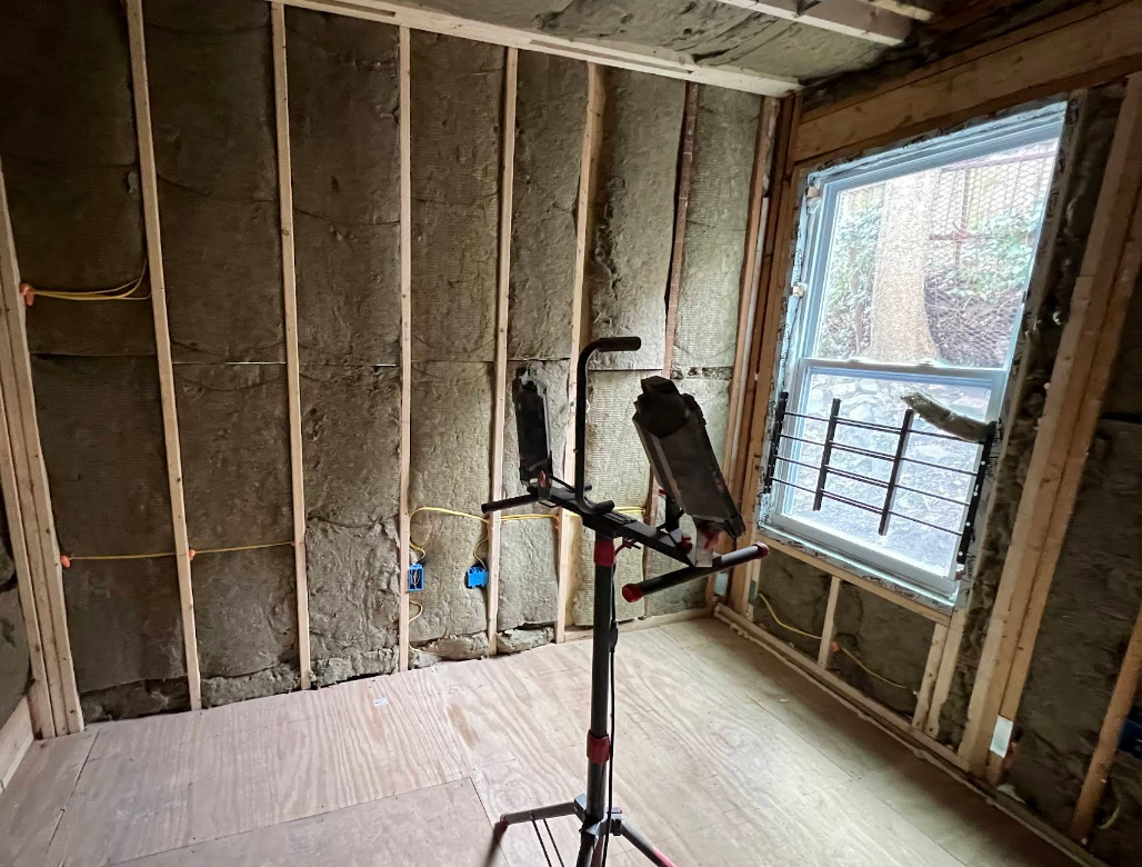 Interior construction with insulation between wall studs, a window, and a work light.