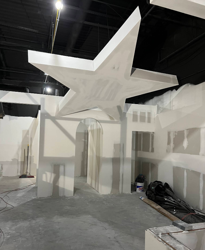An unfinished construction site with white drywall walls and a large star fixture on the ceiling.