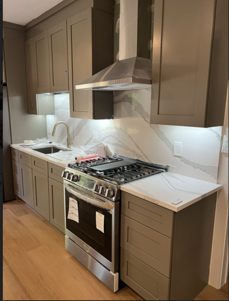 Gray kitchen with stainless steel appliances and marble backsplash.