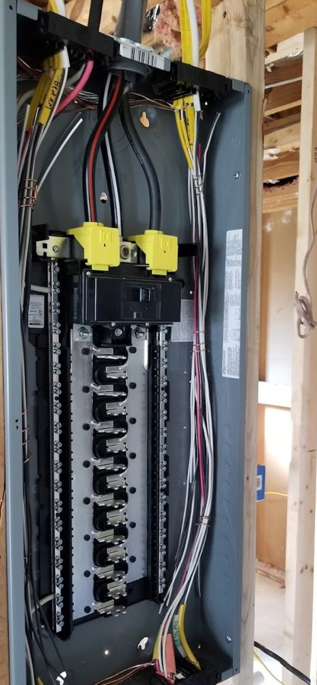 Electrical panel with wires and circuit breakers installed in a wall.