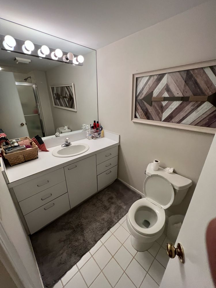 Bathroom with white cabinets, toilet, and patterned artwork on the wall.