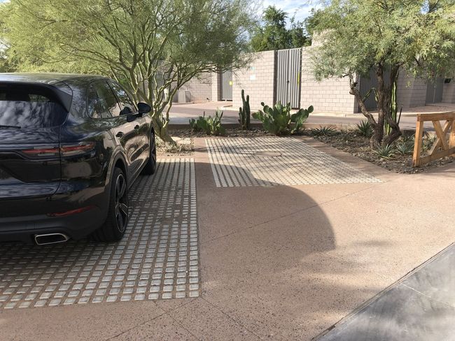 A black car is parked in a driveway next to a house.