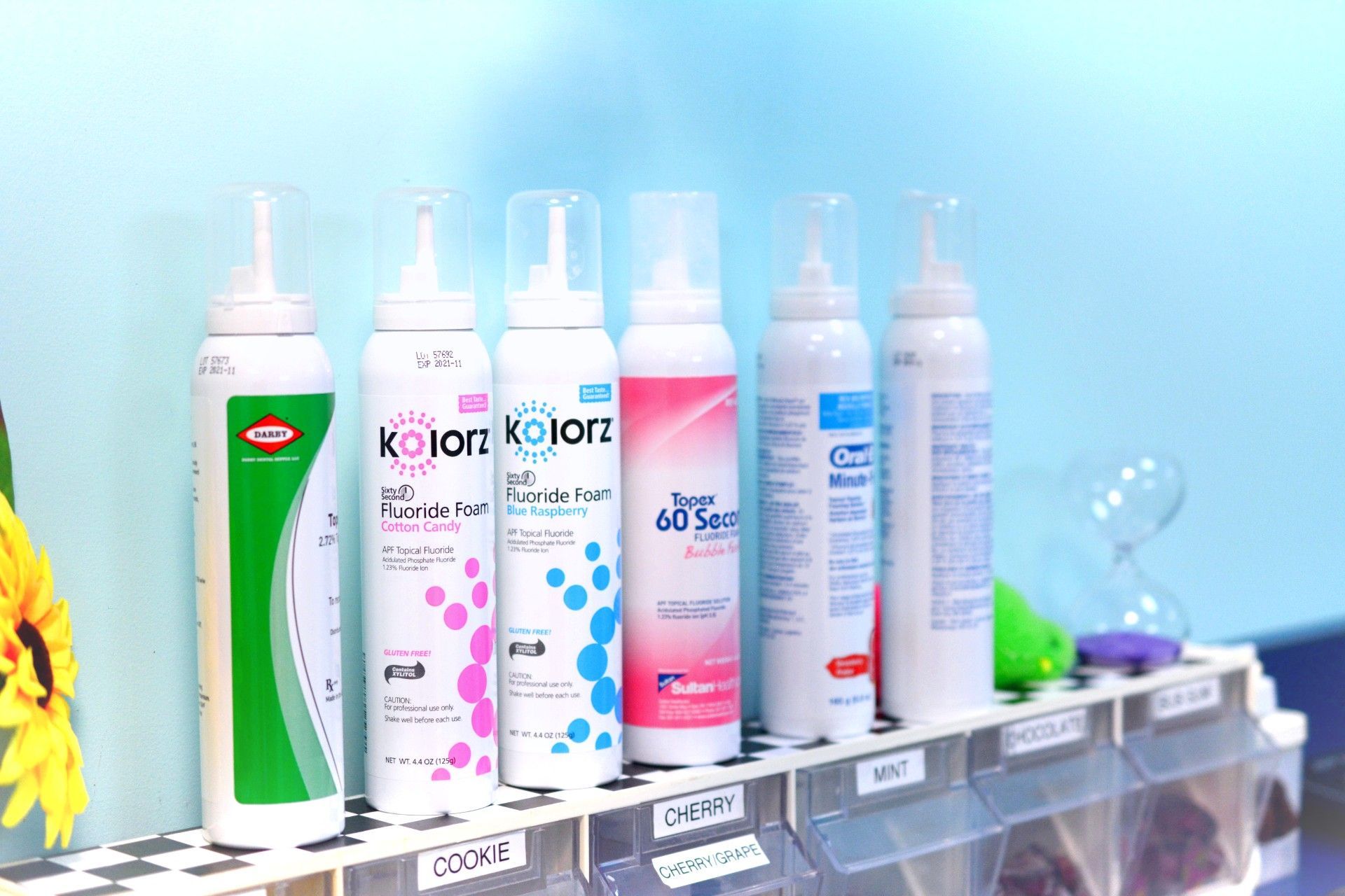 Assorted bottled skincare products displayed on a shelf against a light blue background.