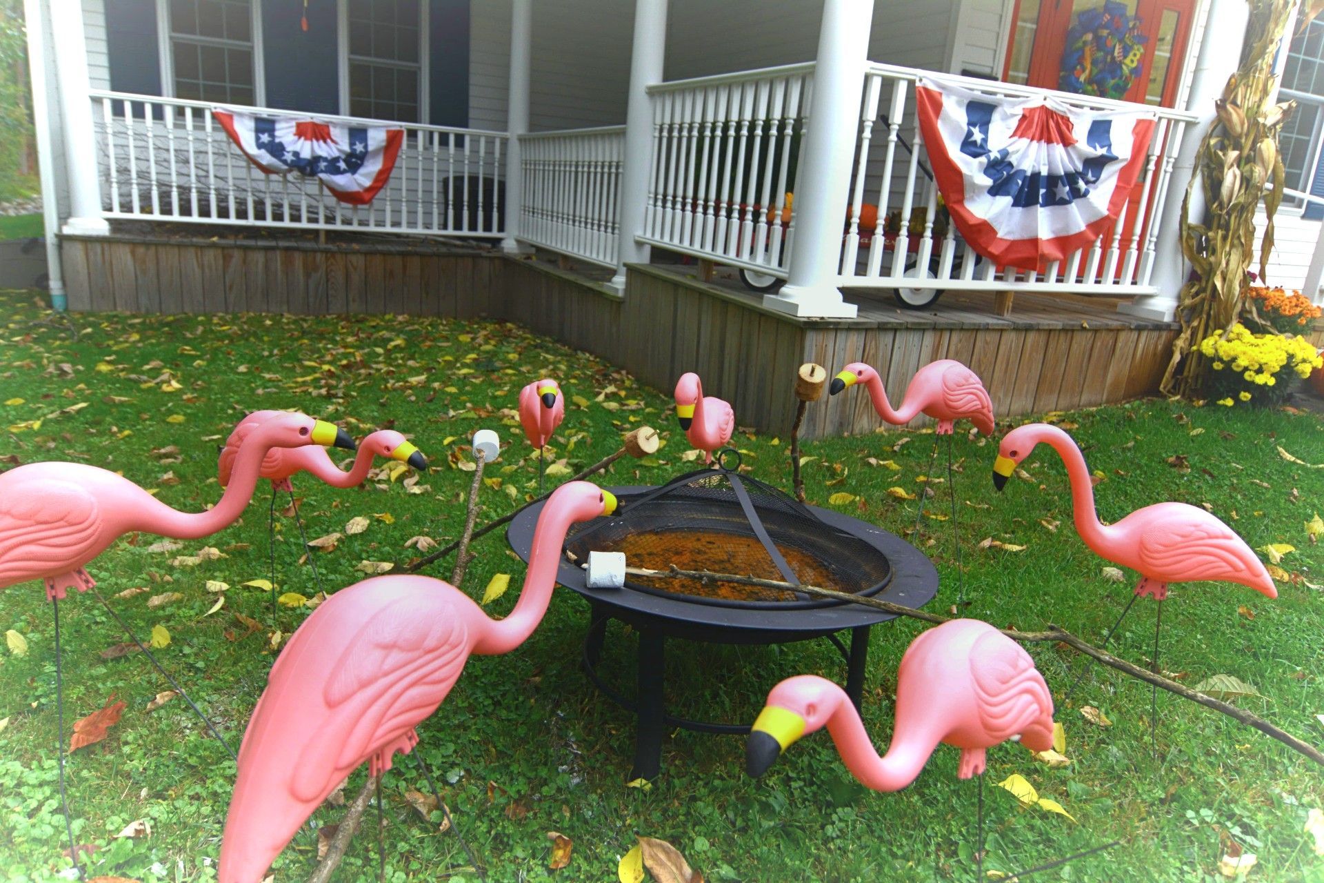 Pink flamingo lawn ornaments around a birdbath in a decorated front yard garden