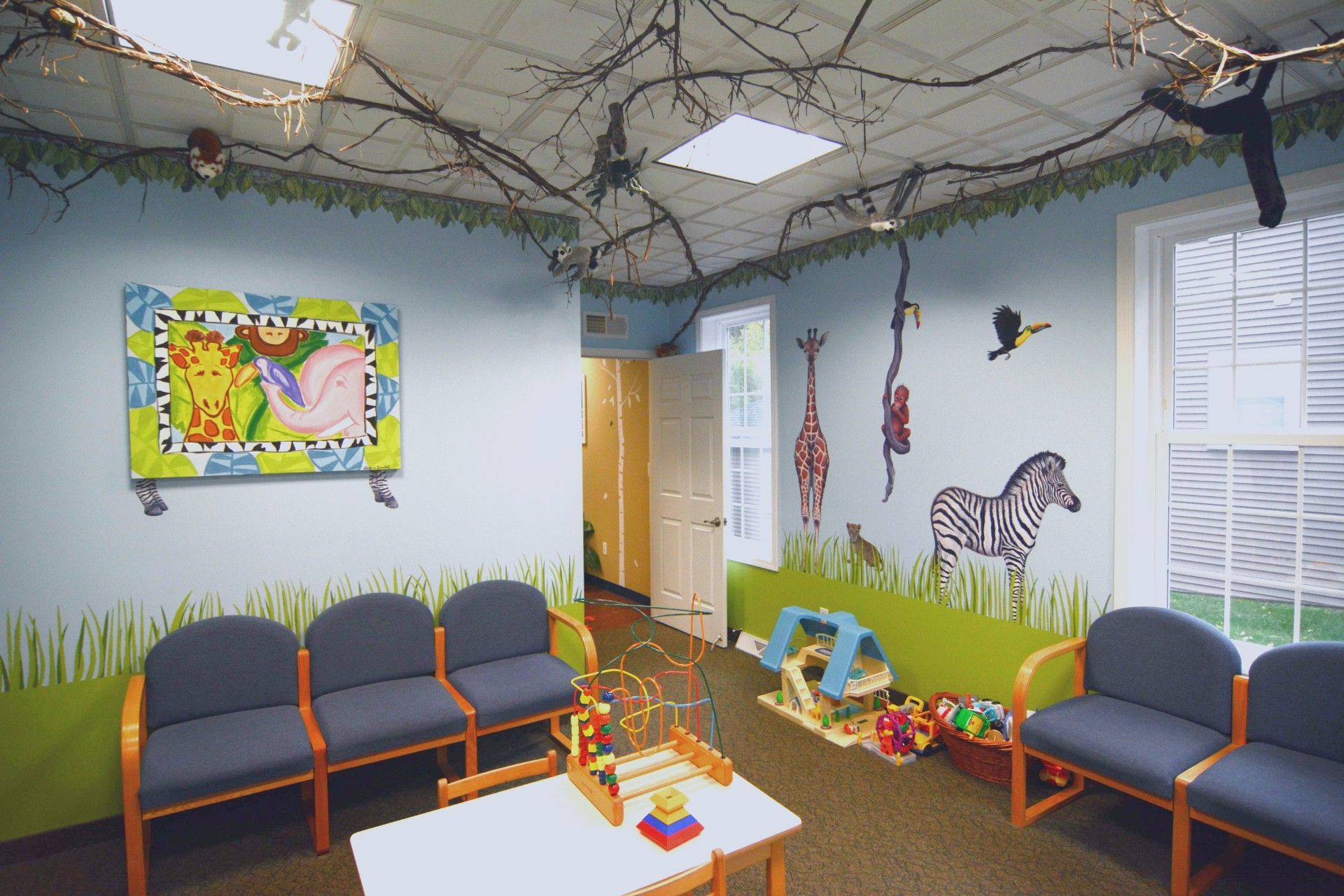 Childcare waiting room with gray chairs, wall murals, toys, and string lights on the ceiling