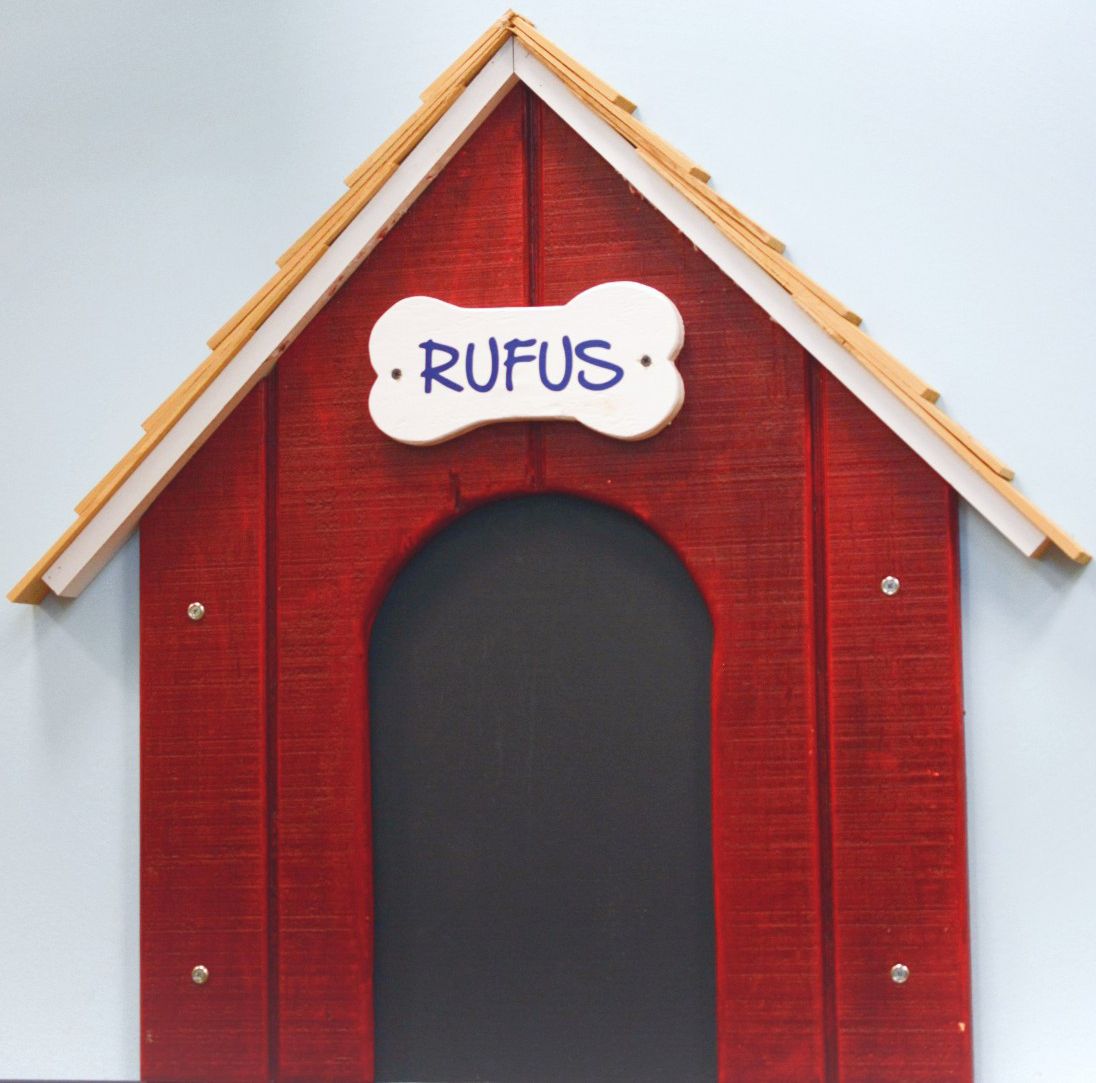 Red doghouse with a white nameplate reading “RUFUS” above the arched entrance.