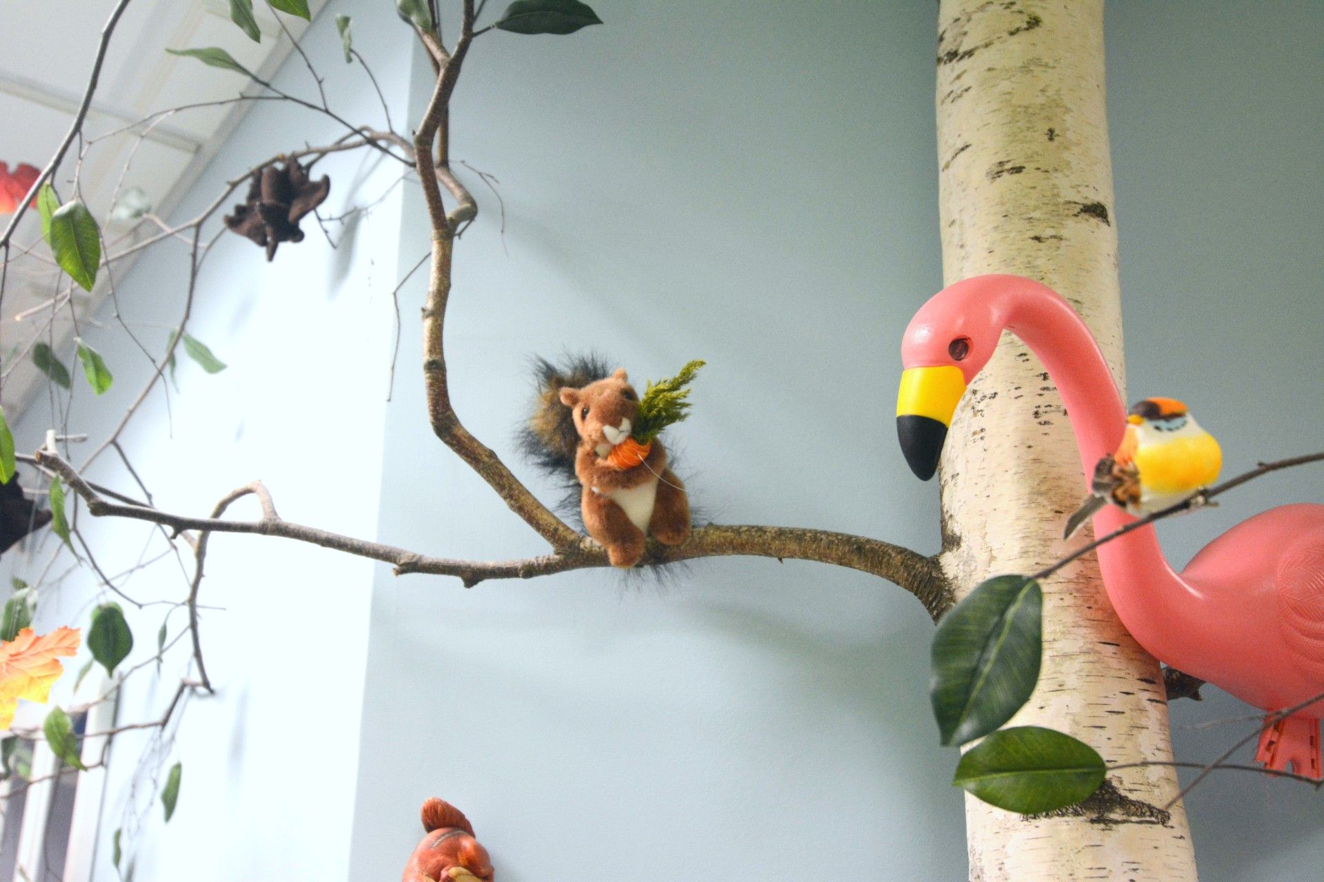 Colorful bird display with faux trees, a flamingo, and small birds on branches